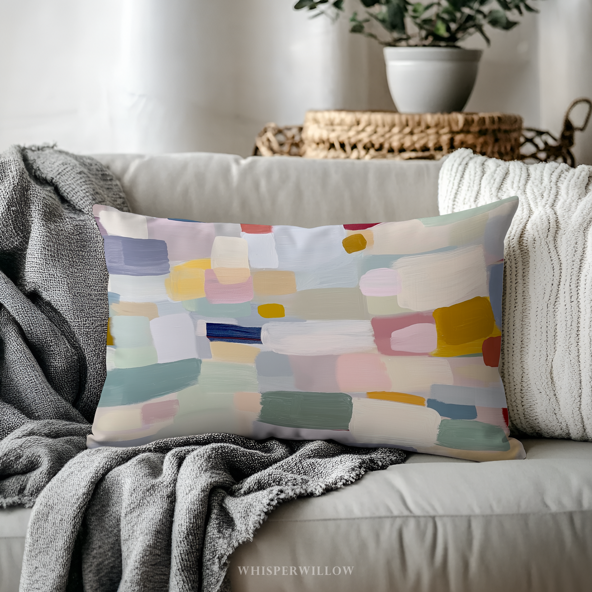 Colorful abstract patterned pillow on a sofa with 'Whisperwillow' branding.